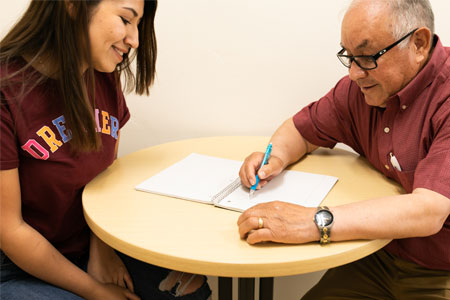 A male and female GED prep student discussing notes