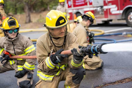 Fire science community college students using a firehose