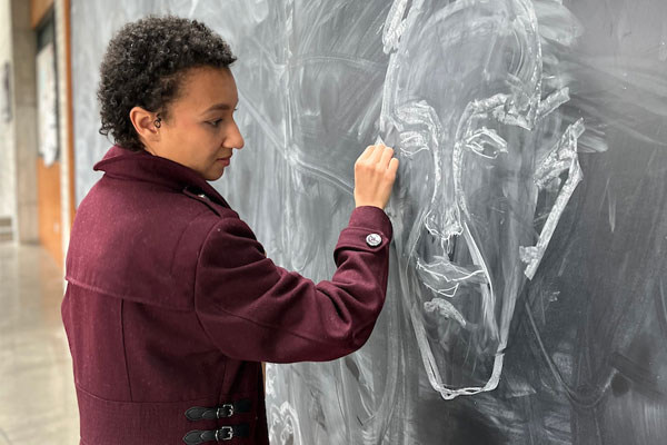 Female art student wearing a red petticoat drawing a man's face on a chalkboard