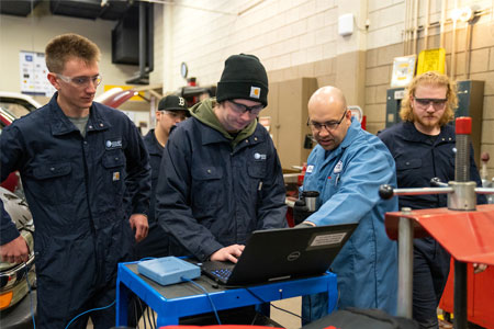 Students gathering around an Automotive Tech teacher.