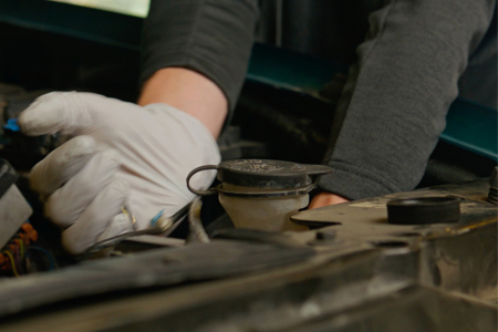 Hands of automotive technician working on car motor