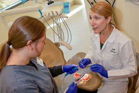 Dental assisting faculty and student working on model of the mouth together