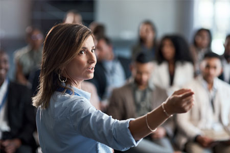 Woman giving an economics lecture to a diverse business audience