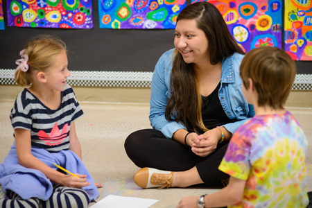 Career Information: community college student educator giving an art lesson to two children