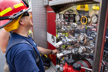 Fire science faculty member in fire figters uniform laughing by side of fire truck