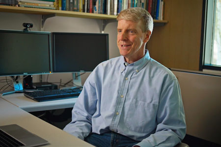 GIS Faculty Member talking from behind work desk with computers