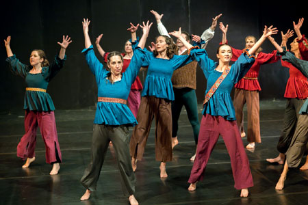 Women dancing in costume with hands in the air. Titled "Modernity".