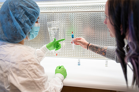 A pharmacy tech student consults with a teacher in the lab.