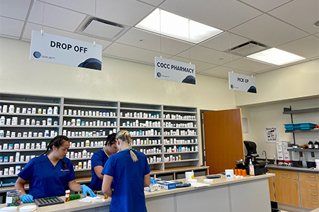 Three pharmacy tech student work together in the simulated pharmacy classroom.