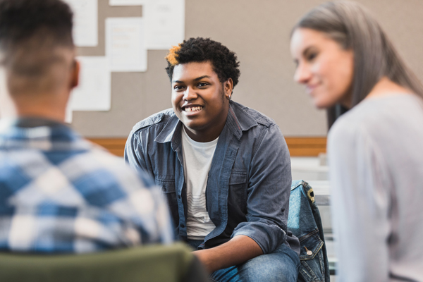 Two psychology students with instructor at COCC. In focus is a black male student, who is smiling.