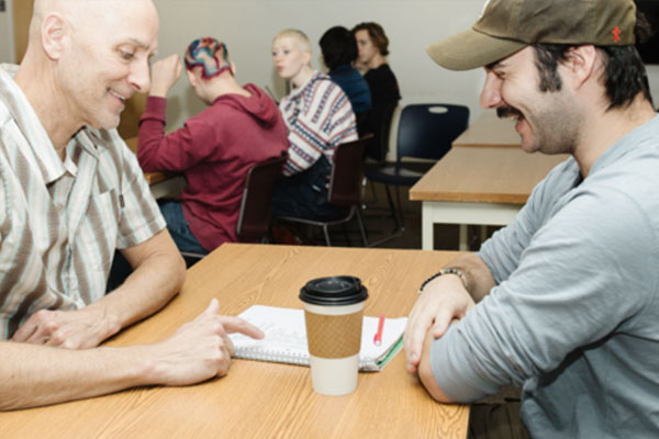 Sociology Teacher and Student Reviewing Notes and Laughing Together