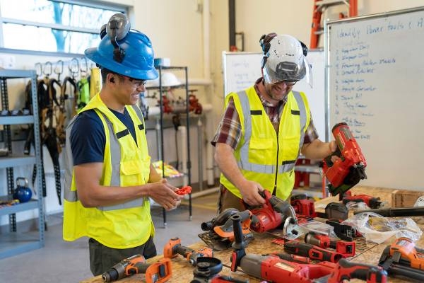 Two apprentices working together in green safety jackets and hard hats